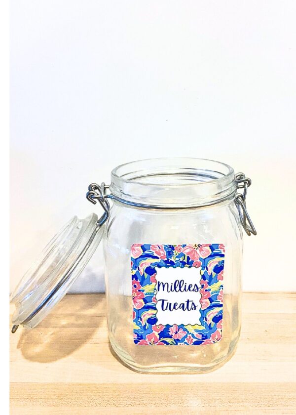 Personalized Dog Treat Jar – Large Glass Dog Treat Container with fun labels. Keep your pup’s favorite snacks fresh and stylishly stored in this charming dog treat jar. Measuring 14 inches round and 6.7 inches tall, this square glass jar with a secure swing-top lid combines functionality with farmhouse-inspired design. The airtight closure locks in freshness, ensuring every biscuit, chew, or treat stays crisp and tasty. What makes it extra special? A custom label personalized with your dog’s name, adding a warm, playful touch that makes this jar as unique as your furry friend. Perfect for countertops, pantries, or as a thoughtful gift for dog and cat lovers, This jar is both decorative and practical. ✔️ Durable square glass design ✔️ Swing-top lid for airtight freshness ✔️ Generous 14” round x 6.7” size to hold plenty of treats ✔️ Customized gingham label with your dog’s name ✔️ Ideal gift for pet parents Customized dog treat jar Width 14.5 inches heght 6.7 inches Laminated Label 3 × 38 oz Bale Square Glass Jar with Swing Top Lid